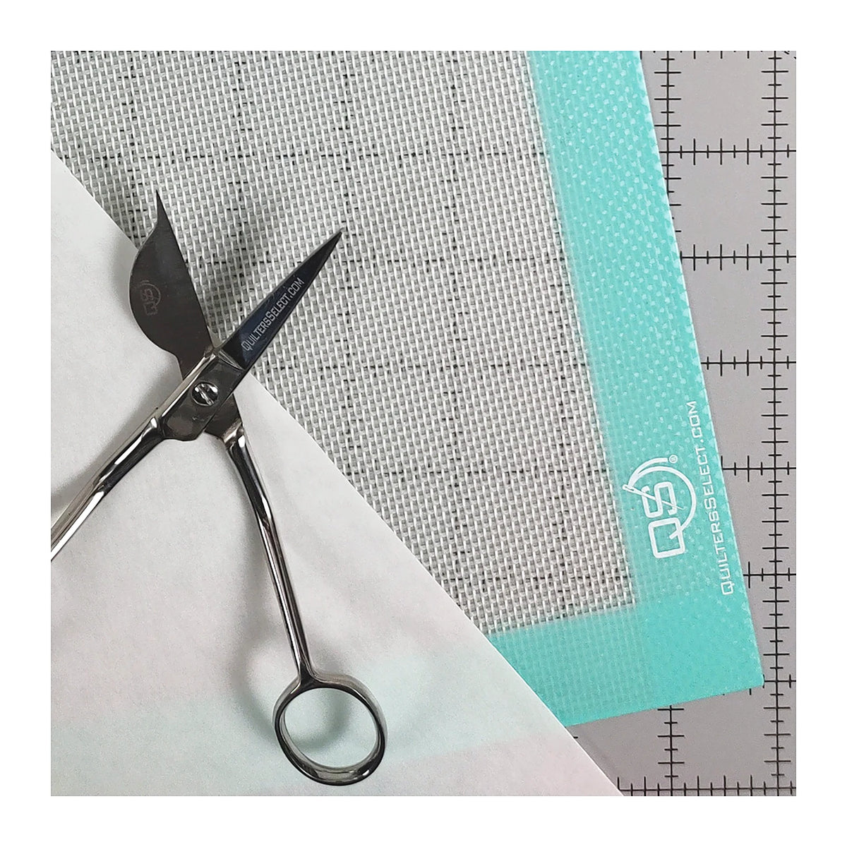 Quilters Select silicone mat in use under fabric and shears, with a gridded ruler alongside